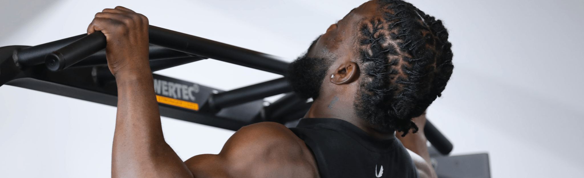 A person performing a strength training exercise on a Powertec Power Rack in a gym.