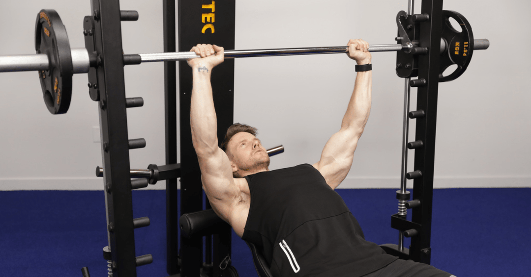Image illustrating a person performing a bench press on a Smith machine.
